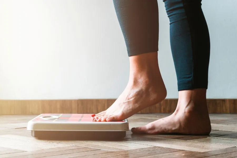 woman checking weight regain on scale